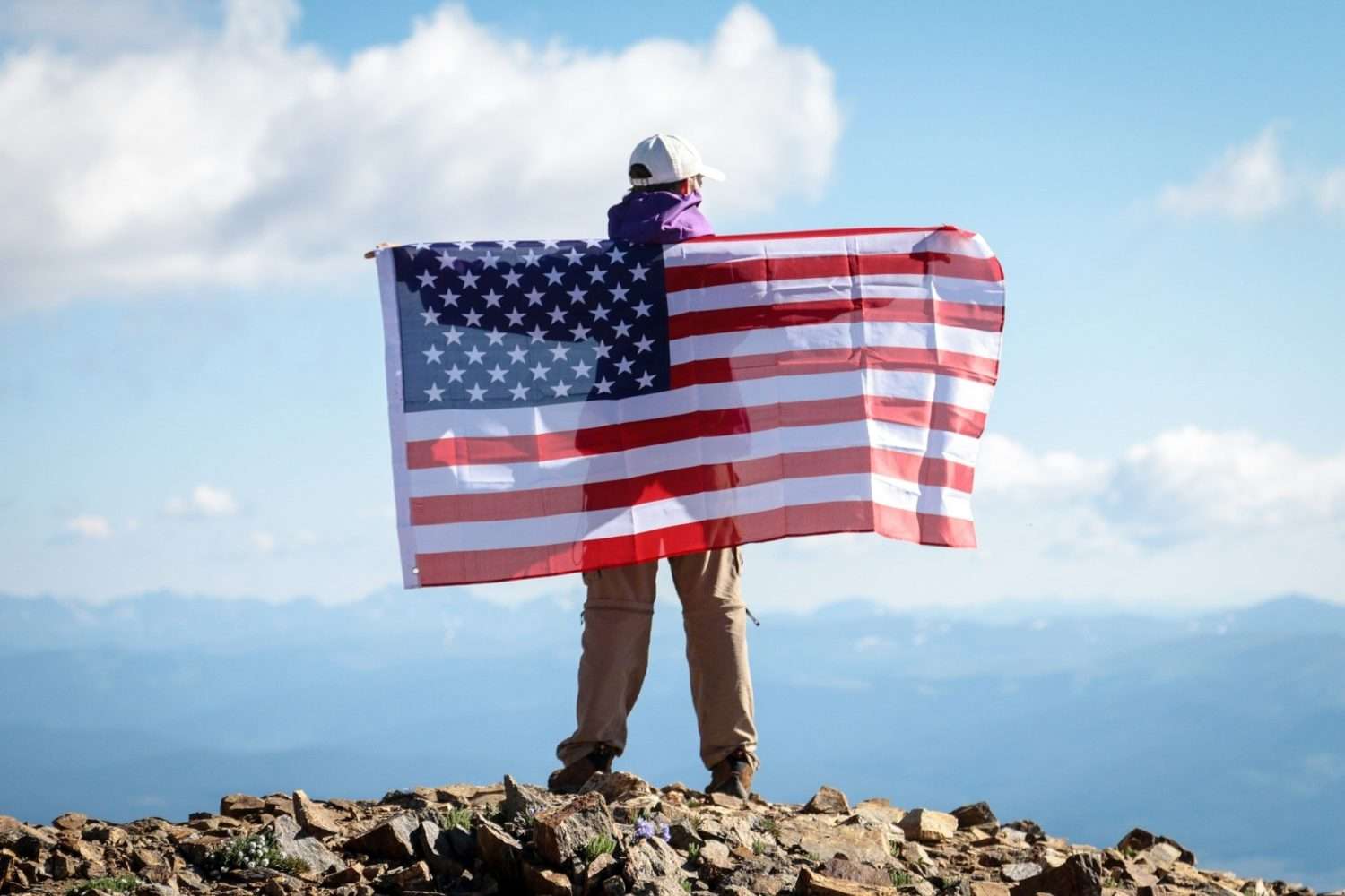 a person holding an American flag on his back.