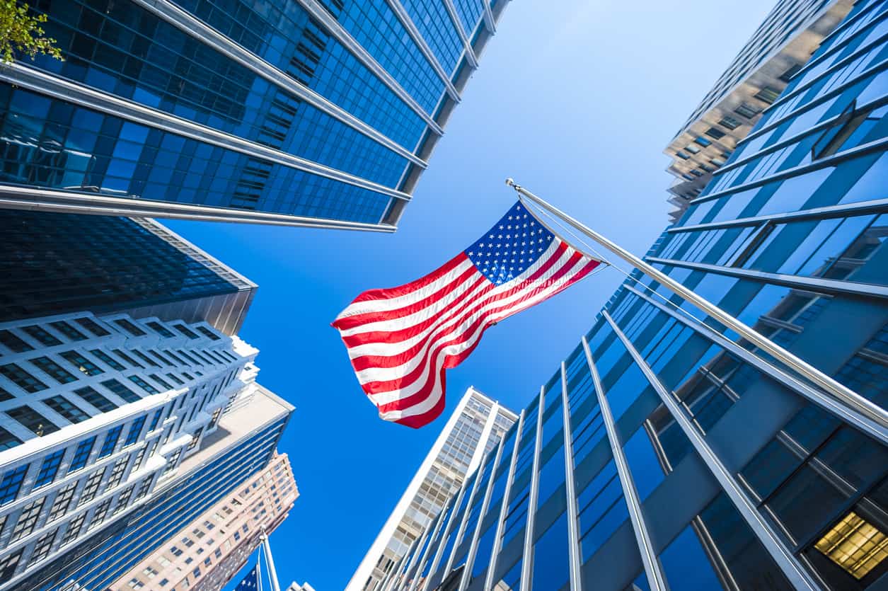 american flag flying infront of a commercial building.