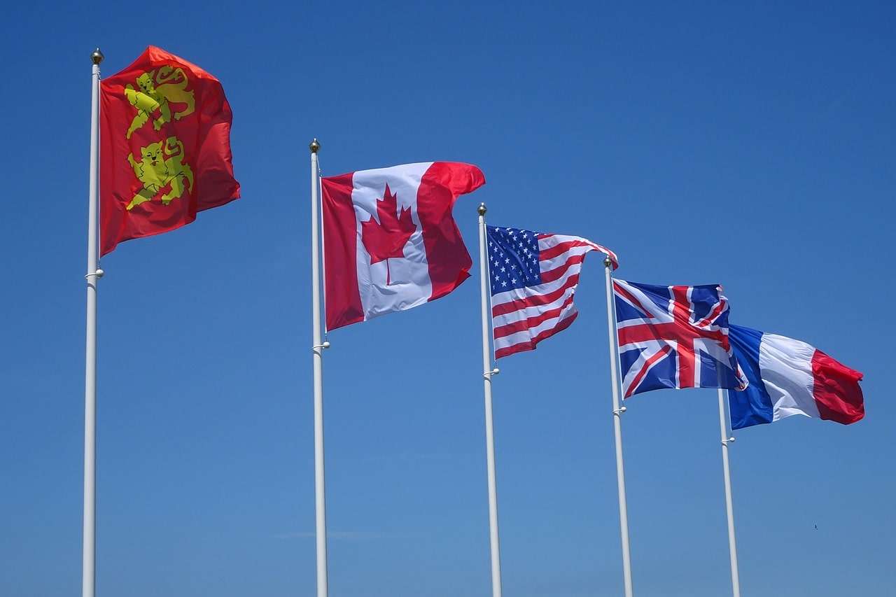 U.S, Canada, UK and France flags flying in the air in picture.