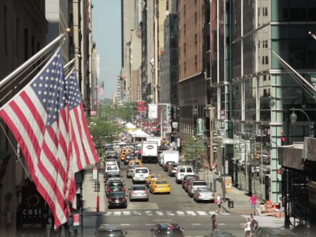 two american flags are flying in a busy street.