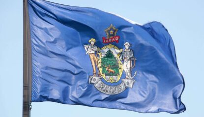 maine state flag flying on a poll
