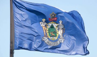 maine state flag flying on a poll